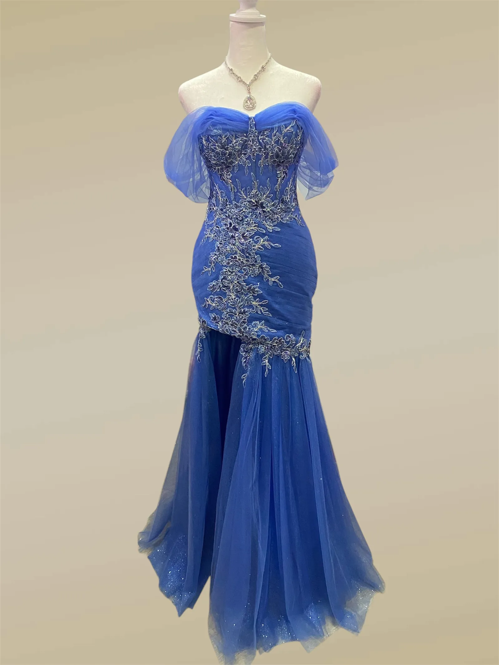 Vestido de Gala Off Shoulder ajustado color Azul decorado con apliques de flores plateados y falda corte sirena con abertura lateral