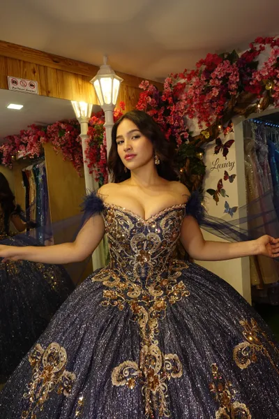Vestido de 15 años Off Shoulder color Navy decorado con apliques y Glitter en dorado y capas en mangas con plumas