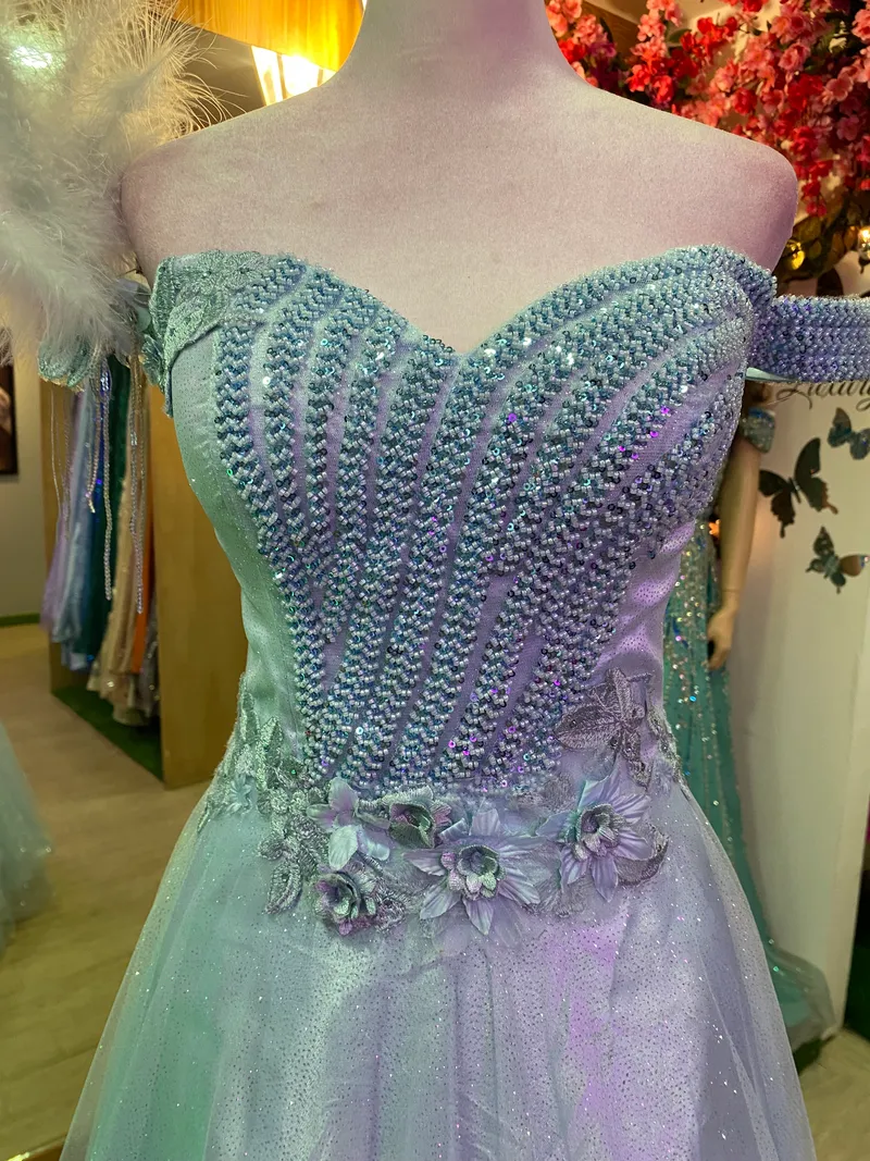 Vestido de Gala Off Shoulder color Celeste falda corte A en tela de Glitter decorado con pedreria y flores en 3D en top
