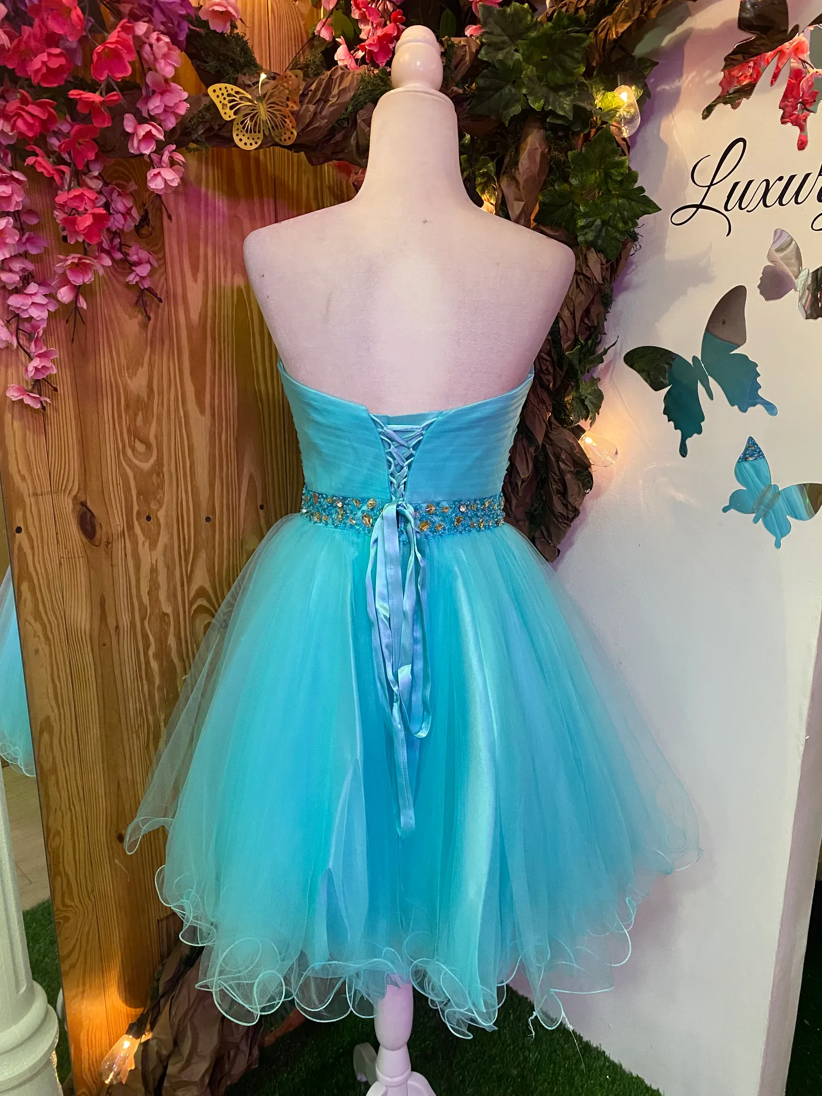 Vestido de Quinceañera corto Strapless con decoraciones de Pedreria en cintura y falda corte A de Vuelos
