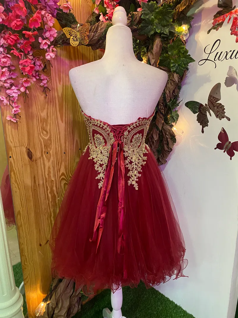 Vestido corto de Quinceañera Strapless decorado con apliques dorados en Top y falda corte A de Tul