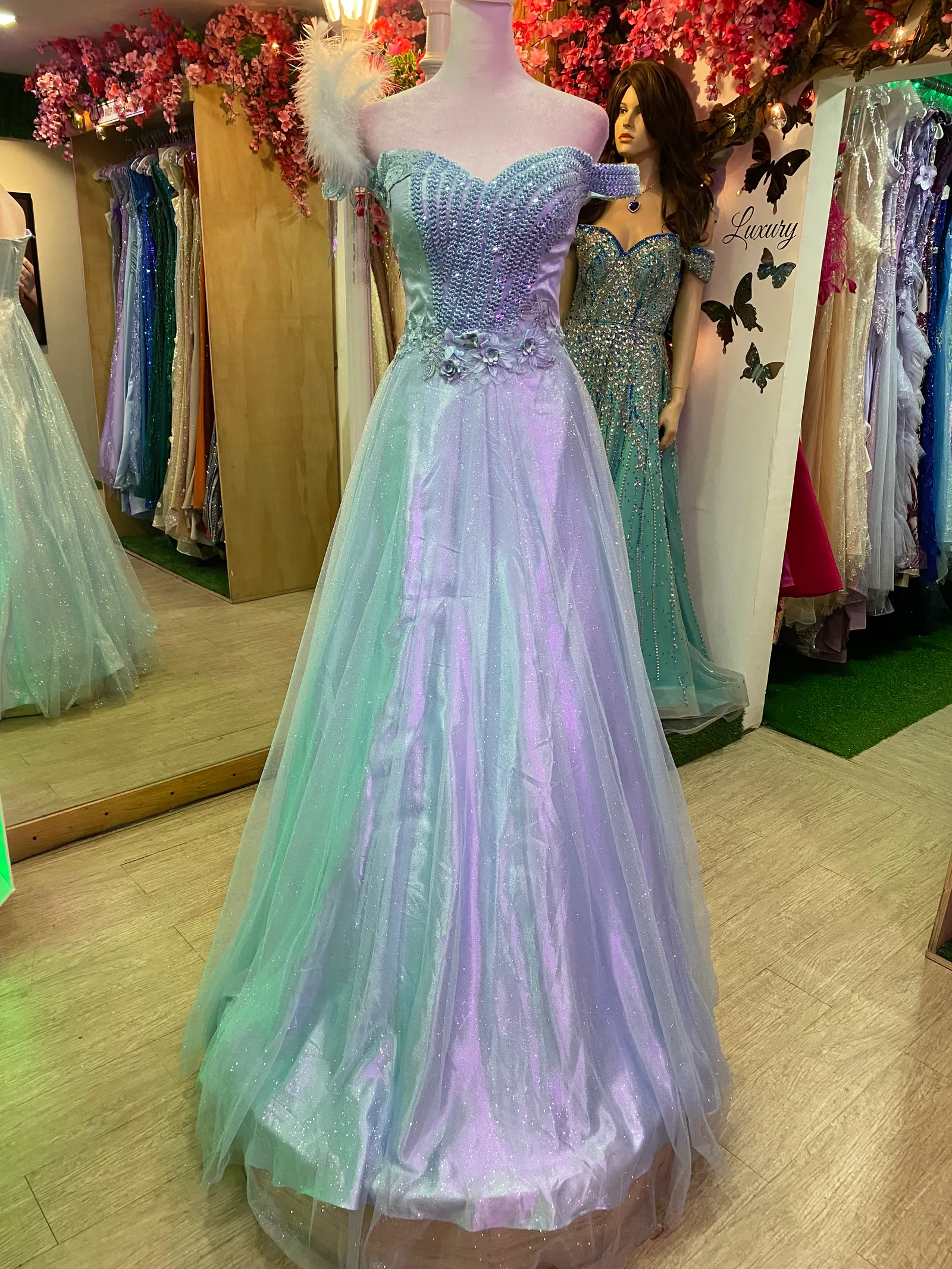 Vestido de Gala Off Shoulder  color Celeste falda corte A en tela de Glitter decorado con pedreria y flores en 3D en top