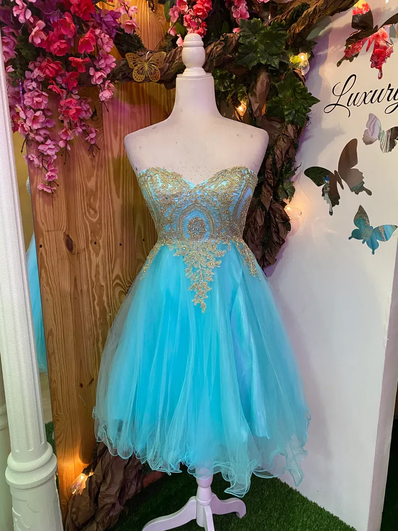 Vestido corto de Quinceañera Strapless decorado con apliques dorados en Top y falda corte A de Tul