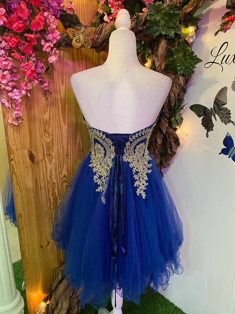 Vestido corto de Quinceañera Strapless decorado con apliques dorados en Top y falda corte A de Tul